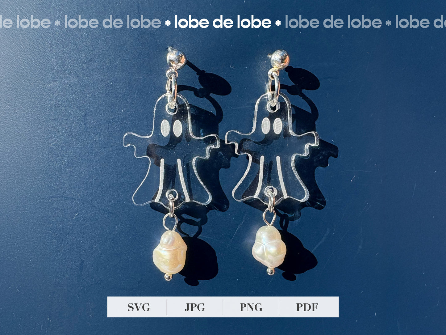 Pair of laser cut and engraved ghost earrings with pearls on a blue background.